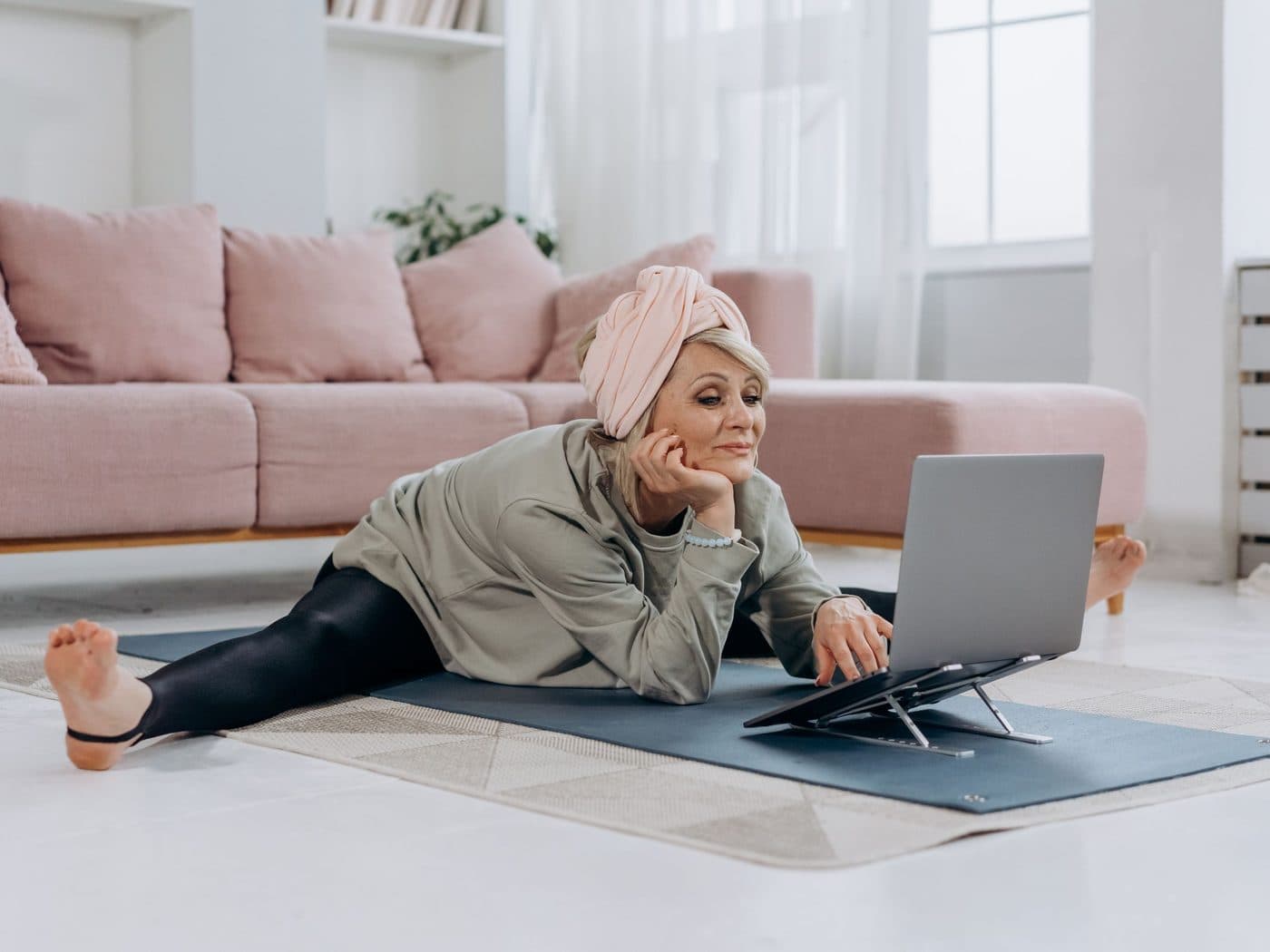 A patient resting on her mat between exercises, smiling at her laptop