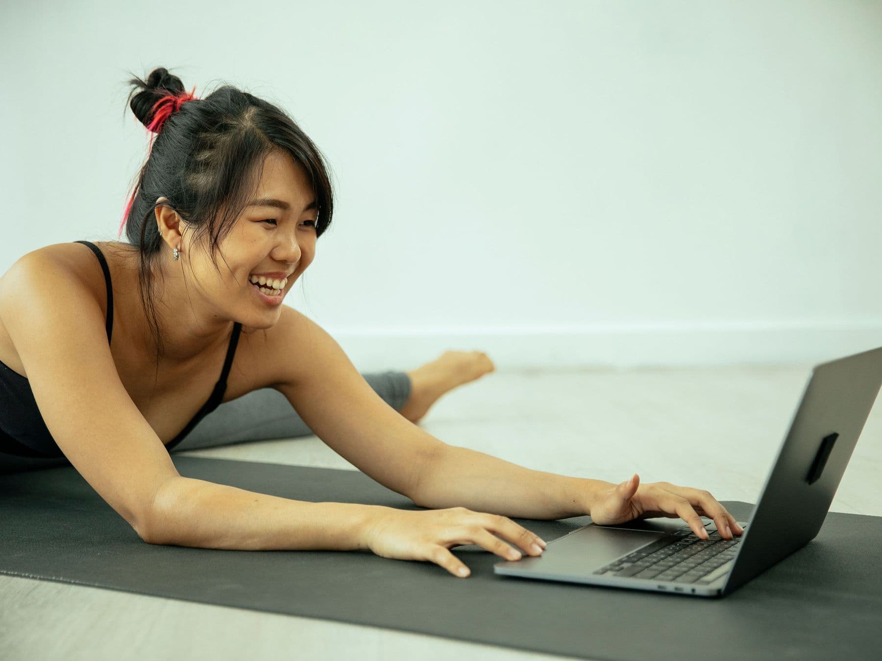 A patient smiling as she works through her exercises at home, laptop open in front of her